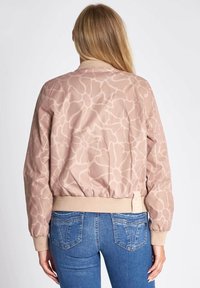 Light pink bomber jacket with abstract cream pattern, ribbed waistband and collar, long sleeves, and a relaxed fit.
