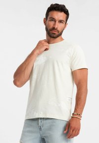 Light beige short-sleeve t-shirt with a subtle abstract pattern, made of soft cotton, featuring a label on the lower side.