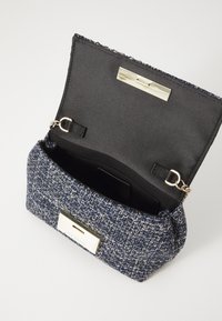 Rechteckige Handtasche aus navy Stoff mit strukturiertem Gewebemuster. Verfügt über ein schwarzes Satin-Innenfutter und einen metallischen Verschluss.