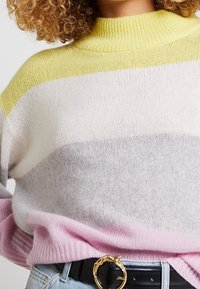 Pull tricoté multicolore présentant un motif rayé jaune, blanc, gris et rose, avec un col montant côtelé et une coupe ample.