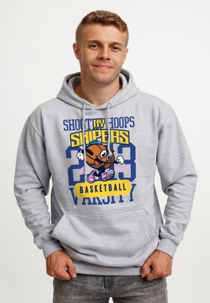 Mężczyzna w szarej bluzie z kapturem z animowaną postacią koszykarza i napisem „Shoot NY Hoops Snipers 23 Basketball Varsity” stoi na białym tle.