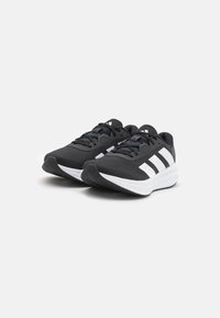 Baskets de sport noires avec une tige en mesh respirant, des accents blancs, trois bandes blanches sur le côté et un col rembourré.
