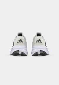 Zwart-witte sport schoenen met een textuur bovenkant en een gevoerde witte zool. Bevat een kenmerkend drie-strepen ontwerp op de hak en gladde accenten.