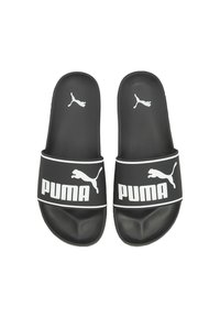 Sandales noires à semelle plate avec une surface texturée, présentant un logo "PUMA" blanc bien visible et une silhouette de chat sautant sur les brides.