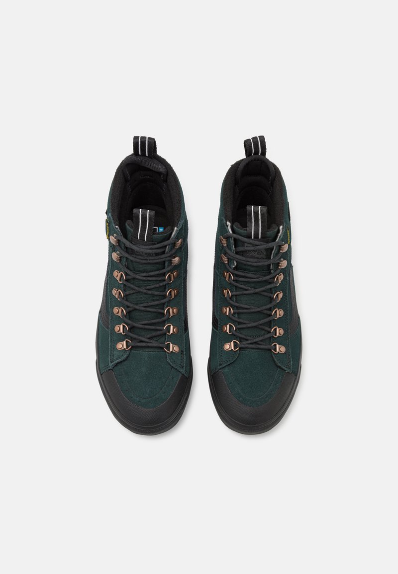 Wysokie buty outdoorowe z ciemnozielonego zamszu, czarnymi akcentami, brązowymi oczkami i teksturowaną gumową podeszwą z wzmocnionym palcem.