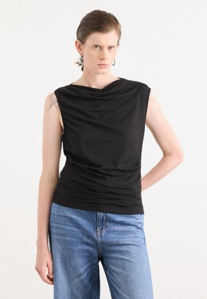 Svart ermeløs topp med drapert halslinning og rynket tekstur, kombinert med lyse denimjeans. Toppen har en glatt overflate og tettsittende design.