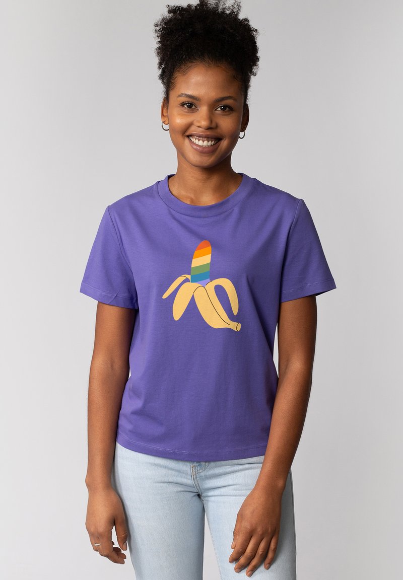 Paarse katoenen t-shirt met een banaan graphic versierd met regenboogstrepen. Ronde halslijn, korte mouwen en een ontspannen fit. Lichtblauwe jeans.