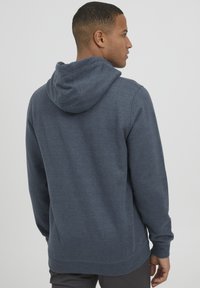 Navyblauwe hoodie met een trekkoord in de capuchon, lange mouwen en een losse pasvorm. Gemaakt van zachte, gestructureerde stof met een geribde zoom.