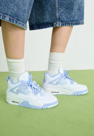 Zapatillas blancas y azul claro con acentos de malla, puntera redondeada, cordones y una unidad de amortiguación de aire, combinadas con calcetines blancos de canalé y pantalones cortos de mezclilla.