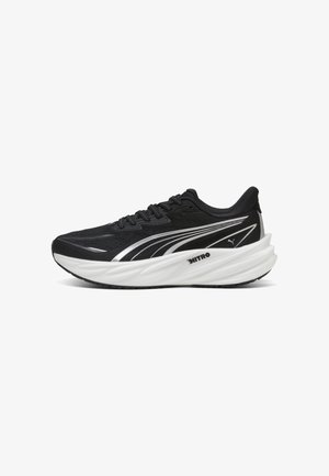 Chaussure de course Puma noir et blanc avec semelle épaisse et rembourrée et marquage Nitro sur le côté, vue de l'extérieur.