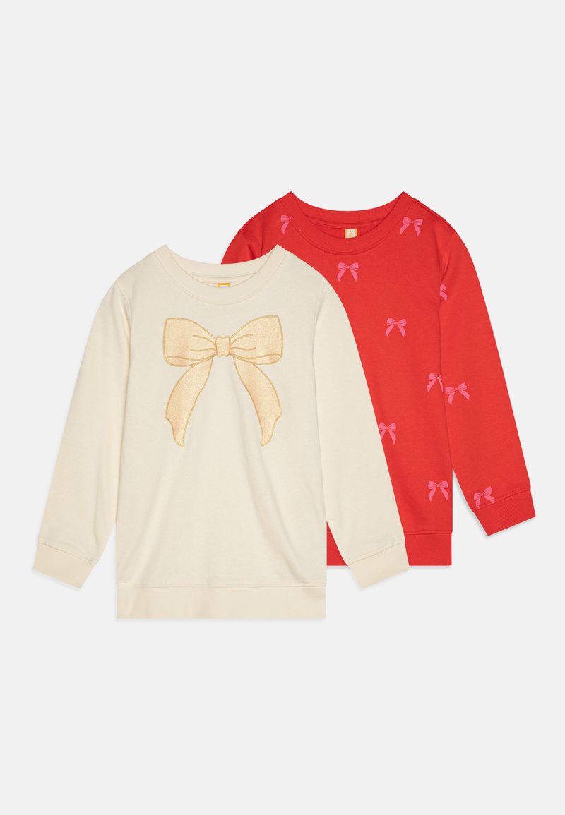 Δύο φούτερ με μακριά μανίκια: ένα κρεμ με γραφικό χρυσού φιόγκου και ένα κόκκινο με επαναλαμβανόμενα μοτίβα ροζ φιόγκων. Υλικό από βαμβάκι, άνετη εφαρμογή.