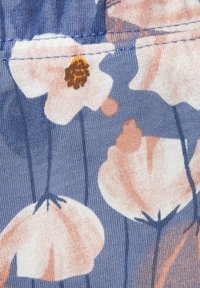Bloemige stof met zachte roze en beige bloemen op een blauwe achtergrond, met een gestructureerd, ribbelpatroon en fijne stiksels langs de naad.