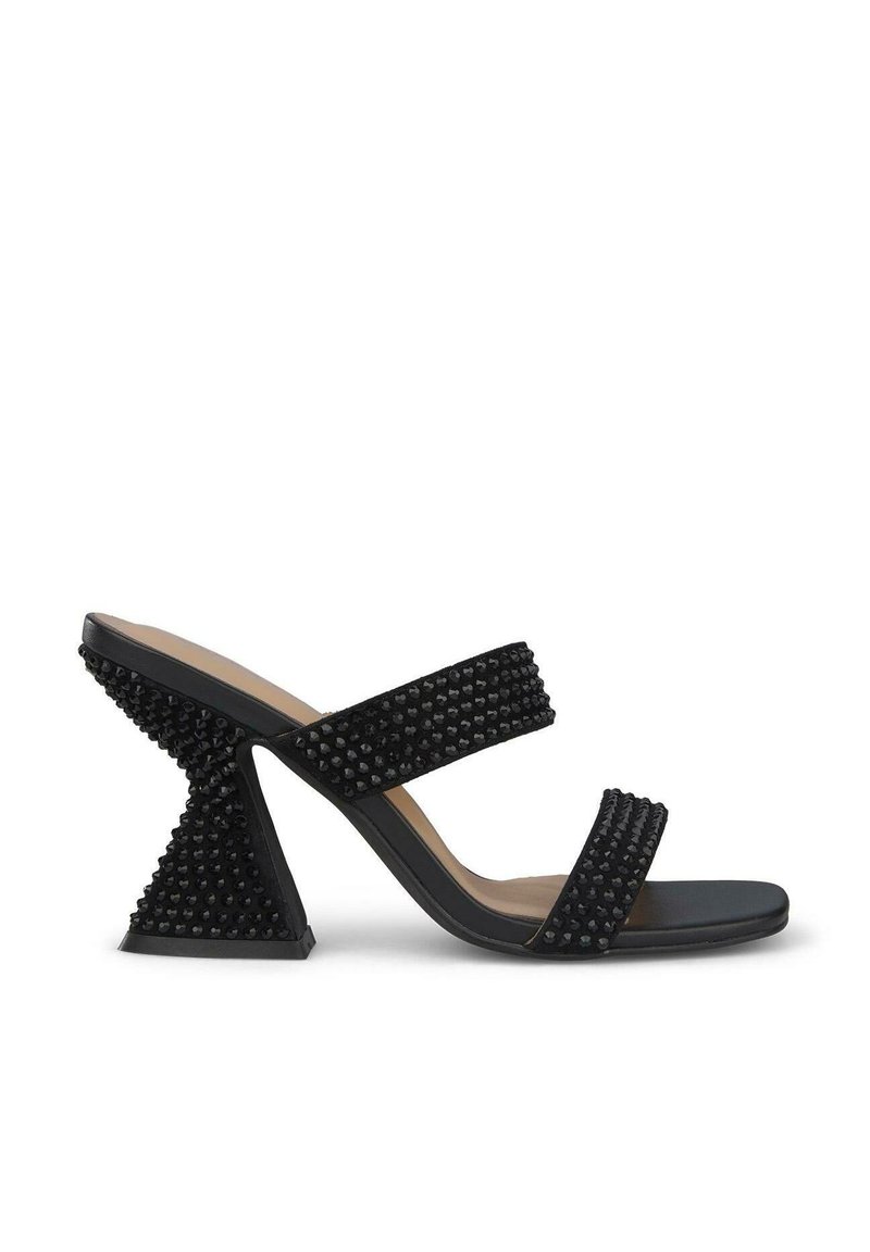Zwarte hoge sandalen met twee brede banden met gestructureerde studs, een open teen en een uniek hoekig hakk ontwerp. Glad, matte afwerking.