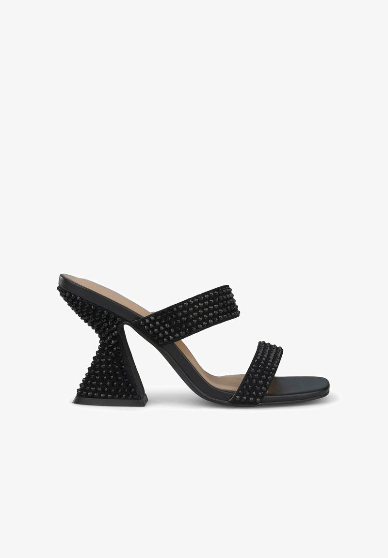 Zwarte hoge sandalen met twee brede banden met gestructureerde studs, een open teen en een uniek hoekig hakk ontwerp. Glad, matte afwerking.