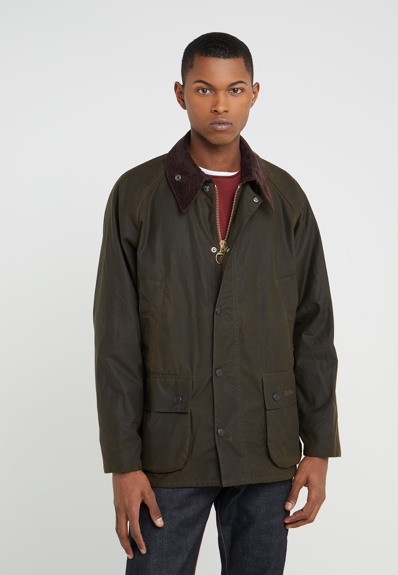 Oak-green jacket with a corduroy collar, featuring two front pockets and a zipper closure. Made from a textured material.