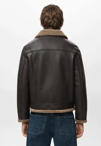 Giacca di pelle marrone con colletto in pelliccia, caratterizzata da un design corto, finitura testurizzata e fodera in tan a contrasto lungo l'orlo e i polsini.