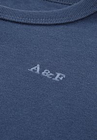 Pull bleu marine en tissu doux, doté d'un col rond et d'un logo "A&F" brodé en bleu clair en bas à gauche.