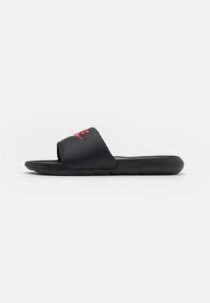 Chanclas negras de diapositiva con una tira ancha que presenta un logo rojo. El diseño incluye una plantilla texturizada y una suela de goma flexible.