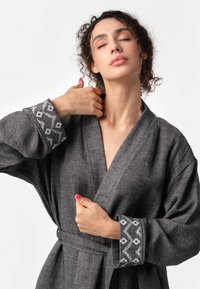 Sivý kimono štýlový župan s textúrovaným povrchom, s dekoratívnymi bielymi geometrickými vzormi na manžetách a so zodpovedajúcim opaskom.