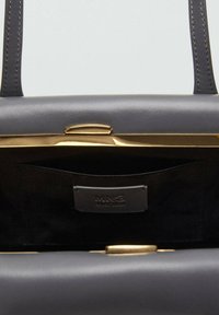 Borsa in pelle grigia con una superficie liscia, hardware dorato e interno nero con tasca e etichetta del marchio.