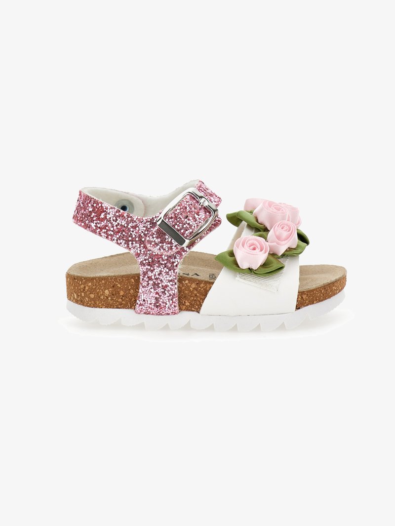 Sandalia con tirantes de purpurina rosa que presenta una plantilla blanca, suela de corcho y flores decorativas de imitación en la parte frontal. Diseño texturizado y cómodo.