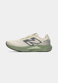 Laufschuh mit einem strukturierten, hellen Creme-Obermaterial, einem grauen Seitenlogo und einer grünen Zwischensohle mit einem dreieckigen Design. Schwarze Laufsohle.