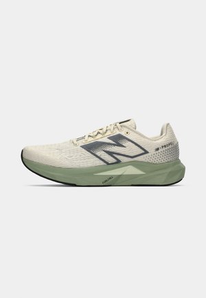Chaussure de course avec une tige en crème clair texturée, un logo gris sur le côté et une semelle intermédiaire verte avec un design triangulaire. Semelle extérieure noire.