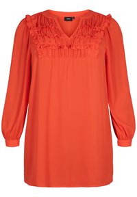 Blouse à manches longues et col en V de couleur orange vif, avec des volants verticaux sur la poitrine et des manches froncées. Texture de tissu lisse.