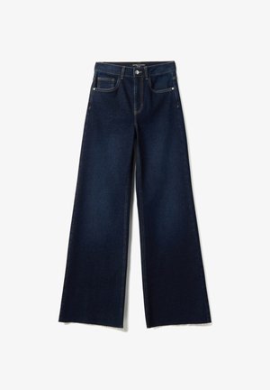 Jean denim bleu foncé à jambes larges avec cinq poches, fermeture par bouton et ourlets bruts, posé à plat sur un fond blanc.