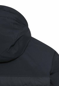 Marineblauwe jas met capuchon, gladde textuur en subtiel verticaal patroon aan de achterkant. Zichtbare stiknaden langs de naden.