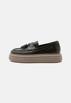 Sort læderloafer med kvaster på toppen og tyk beige rillede platformssål, vist fra siden på en ensfarvet baggrund.