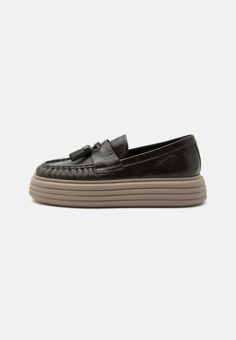 Mocassin en cuir noir avec des glands sur le dessus et une épaisse semelle plateforme beige rainurée, présenté de profil sur un fond uni.