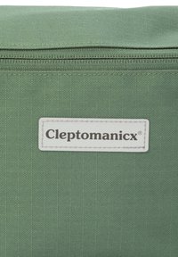 Grüne Stofftasche mit Reißverschluss, versehen mit einem weißen Etikett, das den Markennamen "Cleptomanicx" in fetten schwarzen Buchstaben zeigt.