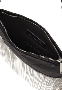 Black leather bag with silver metallic fringe, zip closure, and smooth interior lining. Interior tag visible, showcasing minimal design.