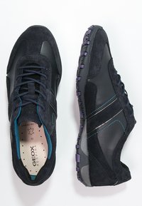 Czarne zamszowe i syntetyczne sneakersy o teksturowanym wykończeniu, z niebieskimi akcentami, czarnymi sznurowadłami oraz wzorzystą podeszwą.