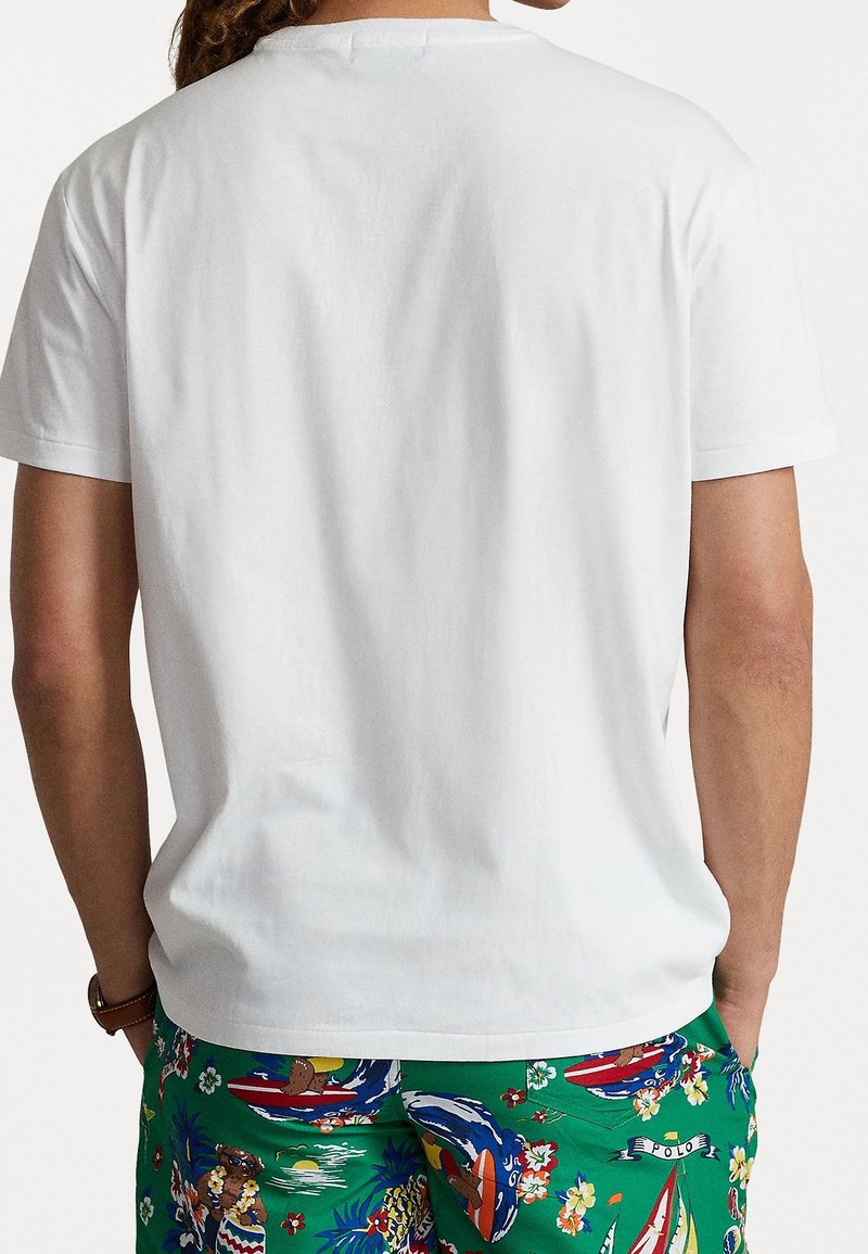 Wit katoenen T-shirt met een ronde hals, korte mouwen en een rechte zoom aan de achterkant, gecombineerd met kleurrijke korte broek met patroon.