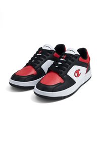 Baskets de sport noires et rouges avec des accents blancs ; matériau en cuir lisse, design à lacets, bout perforé et semelle en caoutchouc.