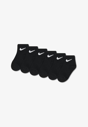 Zes paar zwarte enkelsokken met witte Nike-swooshlogo's in een rij uitgelijnd tegen een witte achtergrond.