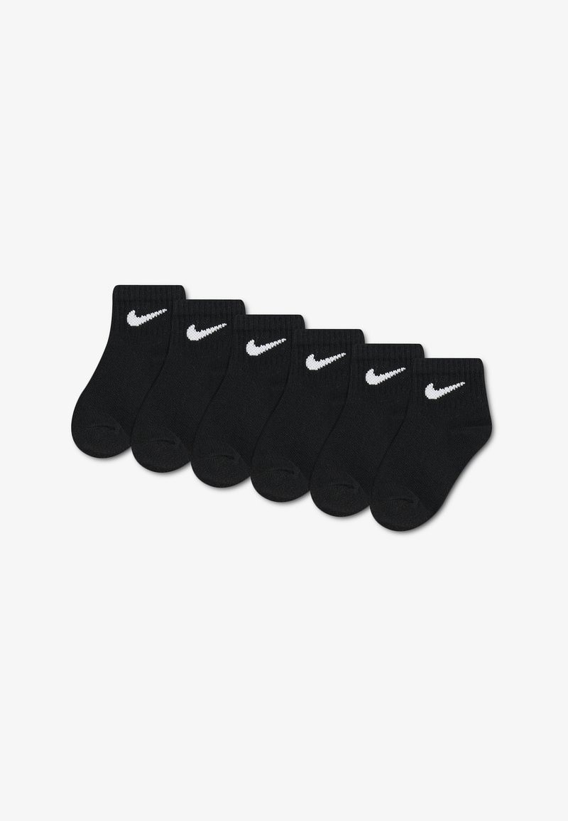 Six paires de chaussettes noires montant à la cheville avec des logos Nike swoosh blancs alignées en rangée sur un fond blanc.