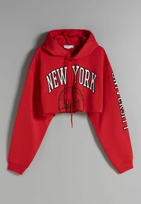 Sudadera corta roja de tela suave, con "NEW YORK" en letras blancas en negrita y detalles gráficos en la parte delantera y la manga.