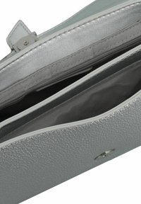 Sac à main métallique argenté avec un extérieur texturé, compartiment zippé et poches intérieures. Doté d'un accent en matériel argenté en forme de cercle.