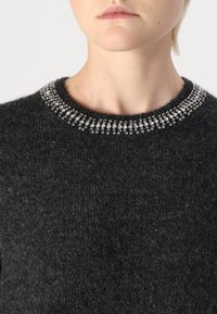 Pull gris foncé à coupe structurée, avec un col rond orné d'une rangée d'embellissements en ton argent le long du col.