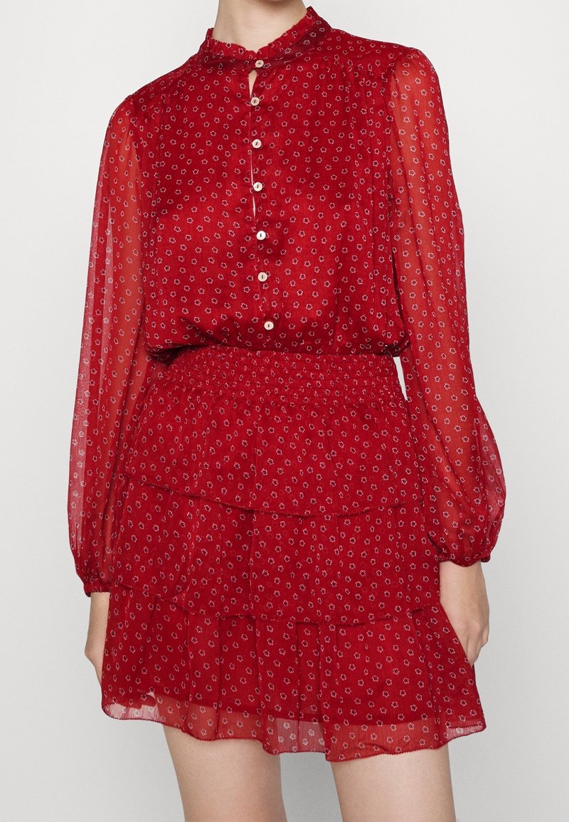 Punainen, läpikuultava mekko puffihihnoilla, nappisuljenta ja kukkakuosi. Sisältää röyhelöistä kerrosta sekä smokkisaumattua vyötäröä tekstuuritakin ilmeen saavuttamiseksi.