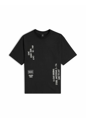Czarny T-shirt z krótkim rękawem i okrągłym dekoltem, z białym pionowym napisem i małą kwadratową grafiką z przodu, zawierający szczegóły marki i wzoru.