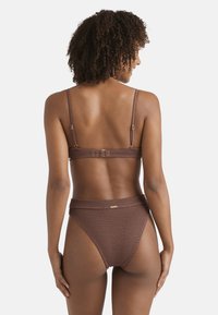 Top bikini brown testurizzato con spalline regolabili e chiusura a gancio, abbinato a pantaloni a vita alta coordinati con un sottile dettaglio del logo.
