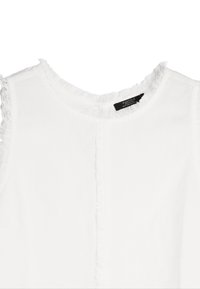 Biała bezrękawnikowa bluzka z okrągłym dekoltem. Posiada postrzępione akcenty wzdłuż szyi i ramion, wykonana z gładkiego materiału.