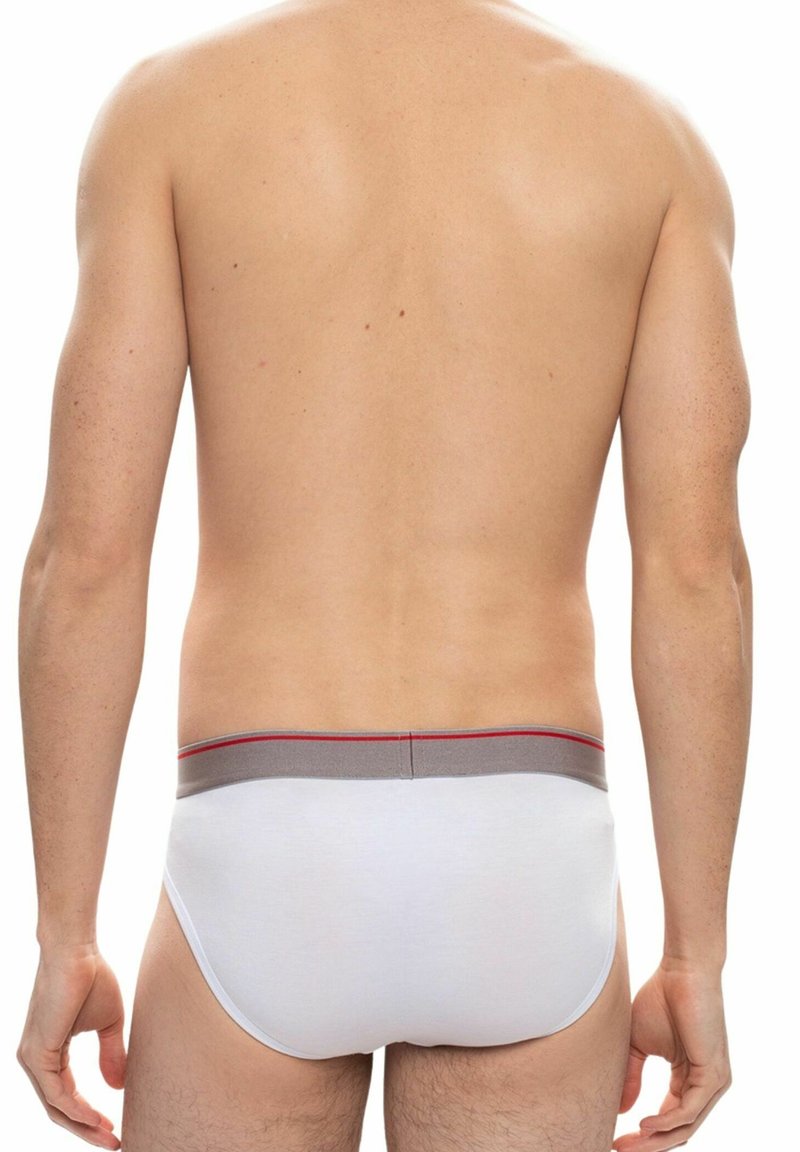 Mutande bianche da uomo con elastico grigio e dettagli rossi, viste da dietro. Il tessuto appare morbido e aderente.