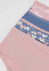 Un montón de cuatro bragas de niña en rosa y azul, con colores sólidos, corazones y patrones de estrellas sobre un fondo blanco.