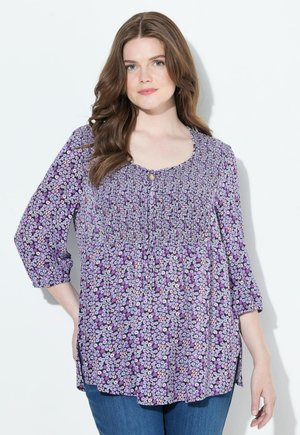 Blusa floreale viola con maniche tre quarti, corpetto arricciato e dettaglio di bottone sul collo. Tessuto morbido con vestibilità comoda.