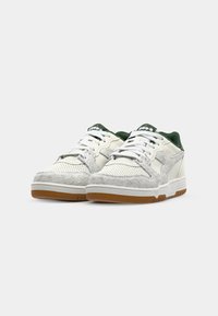 White and grey sneakers with mesh and suede textures, a green accent on the collar, and a gum rubber outsole. Features white laces.